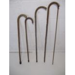 A collection of four vintage wooden walking sticks, along with an alcohol measuring stick