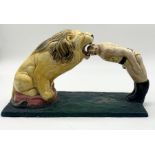 A large ceramic figure of a circus lion and lion tamer with head in his mouth on fibreglass base.