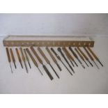 A collection of vintage wooden handled chisels including Marples, along with a hand-made wall