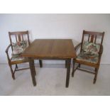 An oak extending dining table, with a pair of matching carver chairs.