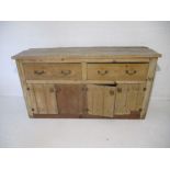 A rustic pine dresser base, with two drawers and two cupboards under, length 173cm, height 92cm.