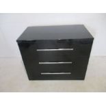 A gloss black chest of three drawers