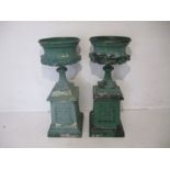 A pair of turn of the century painted cast metal garden urns on plinths, height 123cm.