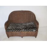 A wicker two seater sofa.