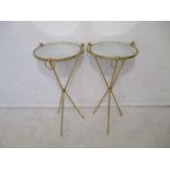 A pair of circular tripod tables with mirrored tops and gilt metal stands.