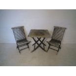 A weathered wooden foldable garden table and two chairs.