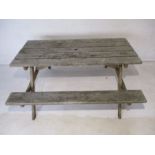 A weathered wooden garden picnic table, marked 'Cosmo'.