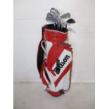 A set of Wilson Staff Fi5 golf irons in a Wilson golf bag. Clubs include irons three to nine and