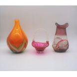 An orange art glass vase, along with a cranberry glass dish and a vase.