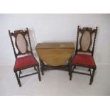 A pair of carved oak chairs, along with an oak drop leaf table with barley twist legs.