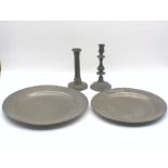 Two pewter plates, along with two pewter candlesticks, with various marks to bases.