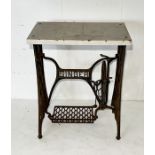 A Singer cast iron treadle sewing machine base with marble top