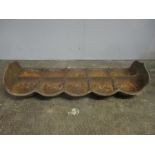 A vintage cast iron pig trough divided into ten feeders.