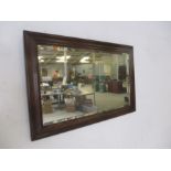 An oak framed mirror with bevelled edge, overall size 98cm x 62cm.