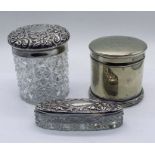 Two hallmarked silver lidded dressing table jars along with a silver plated "Puff Box"
