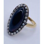 A Georgian/early Victorian unmarked gold ring set with a large cabochon garnet with seed pearl