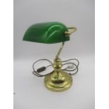 A brass bankers lamp with green shade