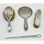 A hallmarked silver mirror along with two similar silver brushes and a silver plated skewer