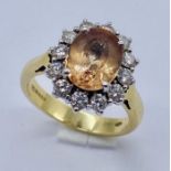 An Imperial Topaz and diamond cluster ring set in 18ct gold, the central topaz measuring approx. 1cm
