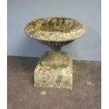 A large reconstituted stone garden urn on plinth, approximate diameter 82cm, height 87cm.