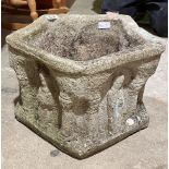 An ecclesiastical style stone planter with carved decorations of apostles.