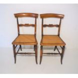 A pair of oak framed chairs with cane seats.