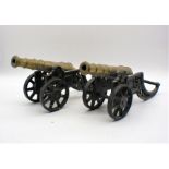 A pair of brass cannons on cast iron bases.