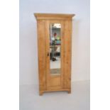 An antique pine single wardrobe with mirrored door, length 146cm, height 215cm.