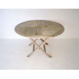 A weathered wooden circular folding garden table, diameter 119cm.
