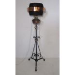A floor standing brass lamp on decorative wrought iron stand, along with a modern shade.