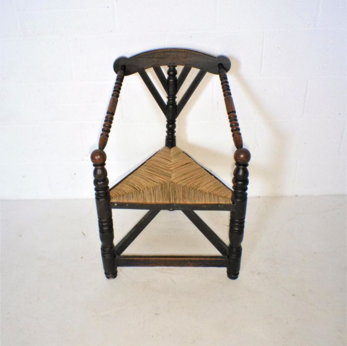 A Liberty style oak corner chair with rush seat.