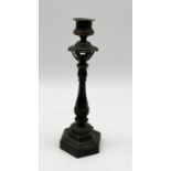 A decorative antique bronze candlestick on octagonal base