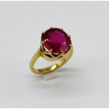 An unmarked gold (tested 14ct) "doll" ring set with a ruby measuring approx. 0.9cm diameter