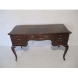 An Edwardian mahogany serpentine fronted ladies writing desk with three drawers, raised on