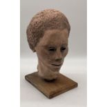 A terracotta bust of an African man on wooden base