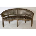 A weathered Cotswold Teak curved garden bench
