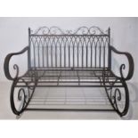 A wrought iron rocking two seated garden bench.