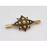 A 15ct gold flower shaped brooch with enamel detailing and set with seed pearls, total weight 7g