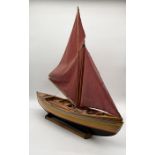 A vintage model of a rowing boat with rudder, plank seats, oars and canvas sails