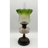 An antique oil lamp with frilled edged green glass shade