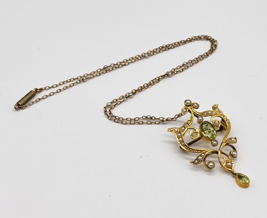 An Art Nouveau 9ct gold pendant set with peridot and seed pearls on an unmarked gold chain set