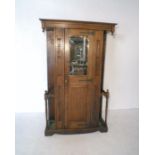 An oak single wardrobe with carved detailing, mirrored door and stick stands either side, length