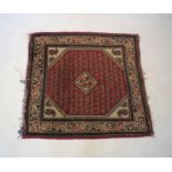 A red ground Eastern rug, approximately 101cm x 93cm.