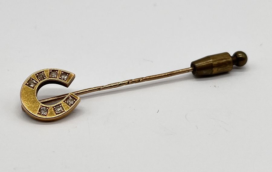 An unmarked gold tie pin in the form of a lucky horseshoe set with diamonds, total weight 2.9g