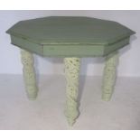 An octagonal two-part painted table with carved legs.