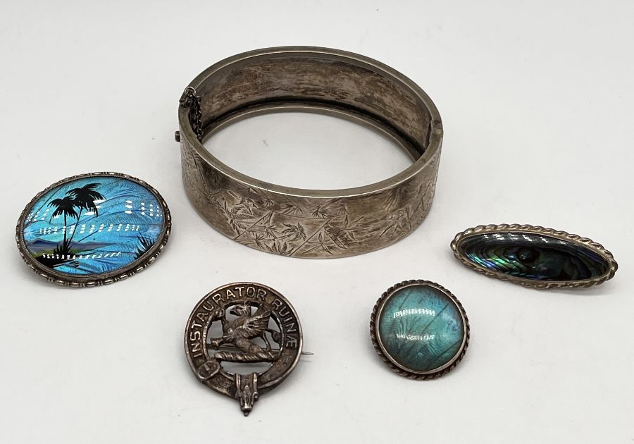 A Sterling silver hinged bangle along with four silver brooches