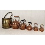 A collection of five copper kettles in decreasing size along with a coal bucket