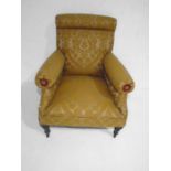 An upholstered Victorian armchair on turned legs.