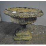 A weathered reconstituted stone garden urn.