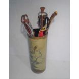 An umbrella stand with oriental decoration with a selection of walking sticks, umbrellas and